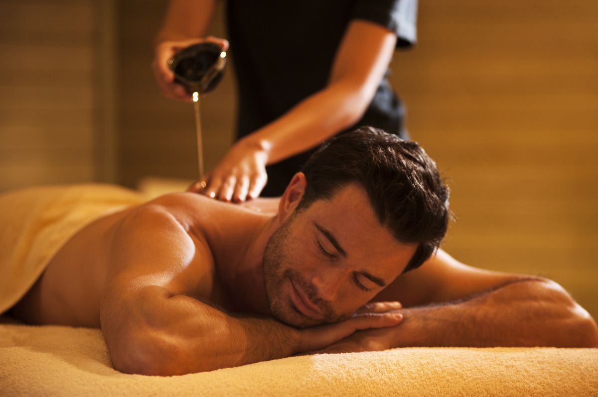 A man feels relaxed at home. A female therapist put oil on his body for the best massage in Dubai.
